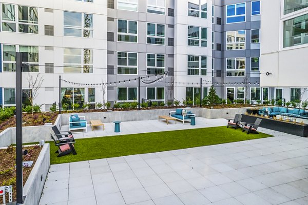 Patio with modern seating and lush greenery at Broadstone Claro Apartments