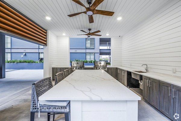 Outdoor grill and patio area adjacent to pool at Atlantic on Romney Apartments, offering luxury amenities for residents
