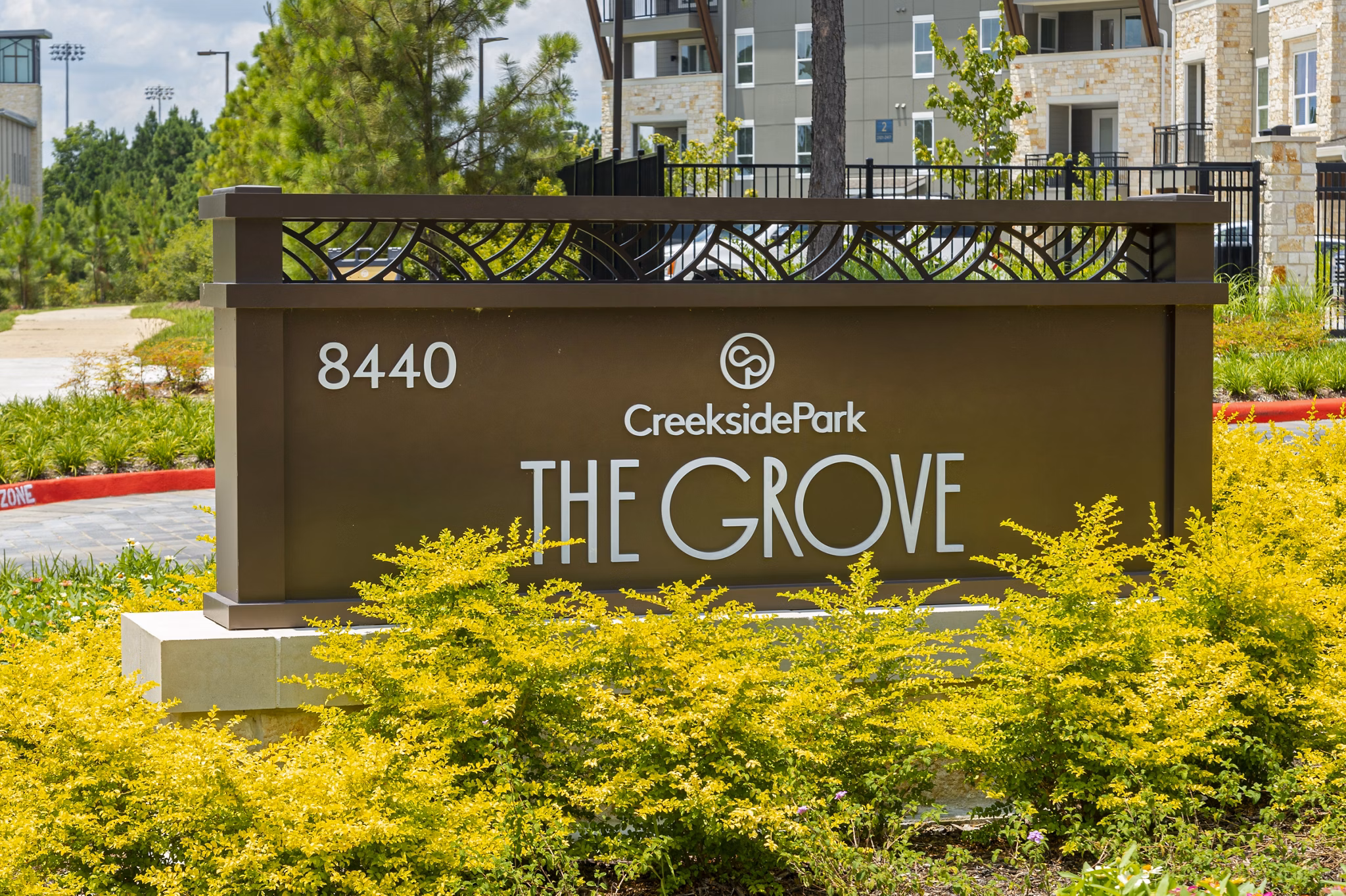 Creekside Park The Grove Apartments signage with lush green landscaping and modern design elements in the background