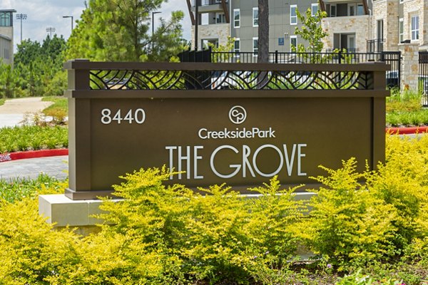 Creekside Park The Grove Apartments signage with lush green landscaping and modern design elements in the background