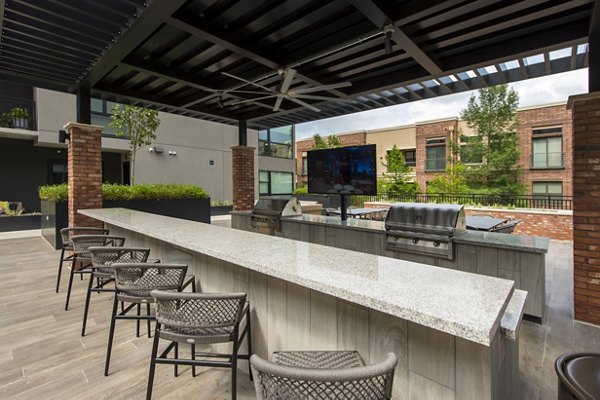 Outdoor grill area with modern seating at The Lane at Waterway Apartments, ideal for entertaining and dining in luxury