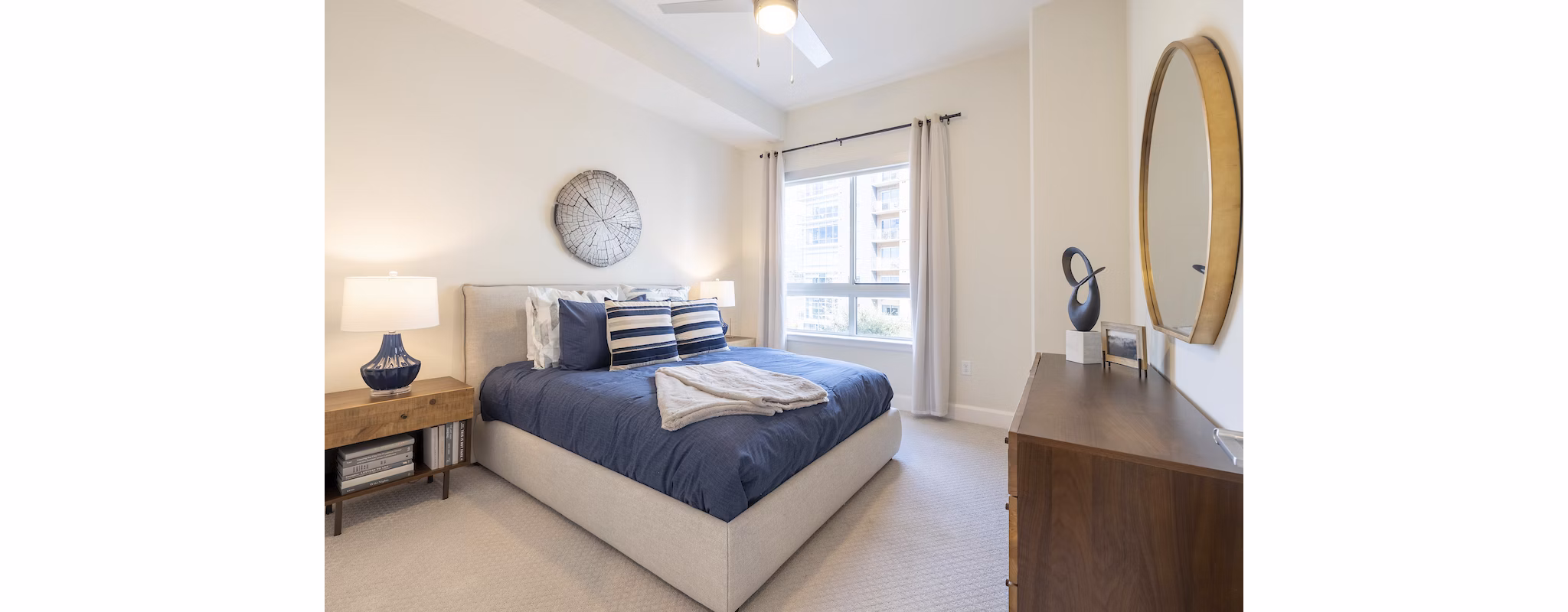 Cozy bedroom featuring a bed, nightstand, lamp, and dresser with natural light from a window
