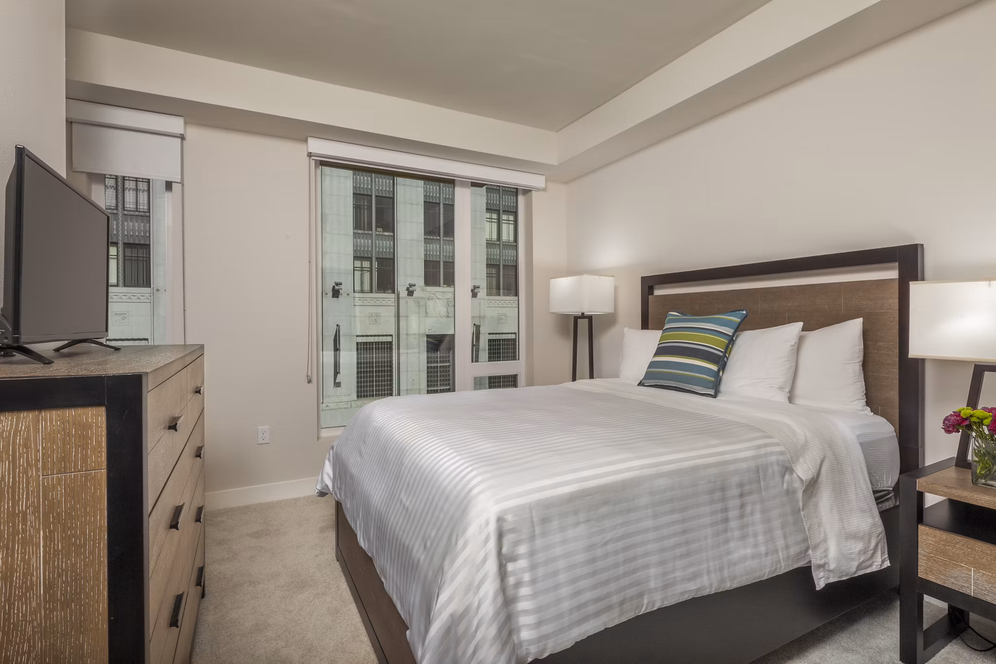 Elegant bedroom with modern decor at mResidences Olympic & Olive Apartments, featuring a cozy queen-size bed and stylish furnishings