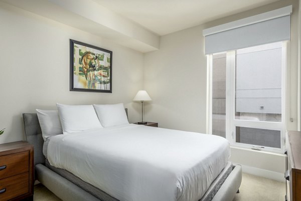 Bedroom featuring modern decor and large windows at mResidences Olympic & Olive Apartments, a Greystar luxury apartment community in a prime urban location