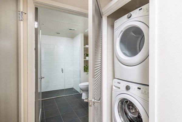 Laundry room equipped with modern appliances at mResidences Olympic & Olive Apartments, offering convenience and style for apartment living