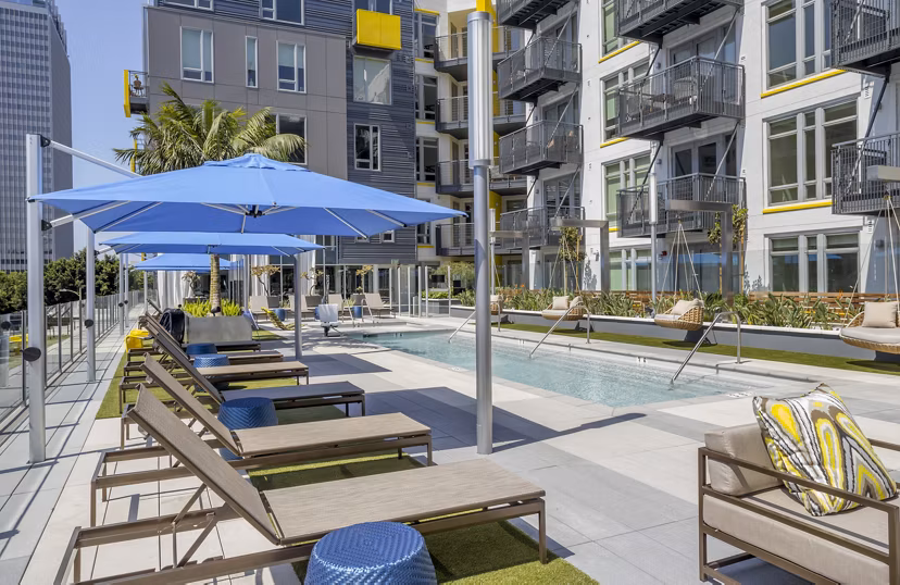 Luxurious swimming pool surrounded by palm trees at mResidences Olympic & Olive Apartments, perfect for relaxation