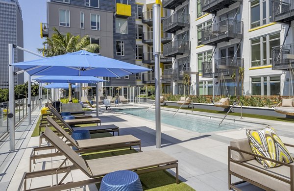 Luxurious swimming pool surrounded by palm trees at mResidences Olympic & Olive Apartments, perfect for relaxation
