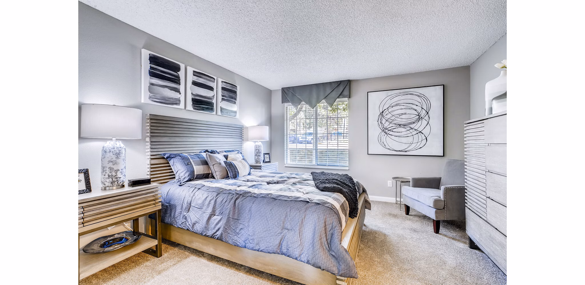 Cozy bedroom with plush bedding and natural light at Loretto Heights Apartments, offering luxury living by Greystar