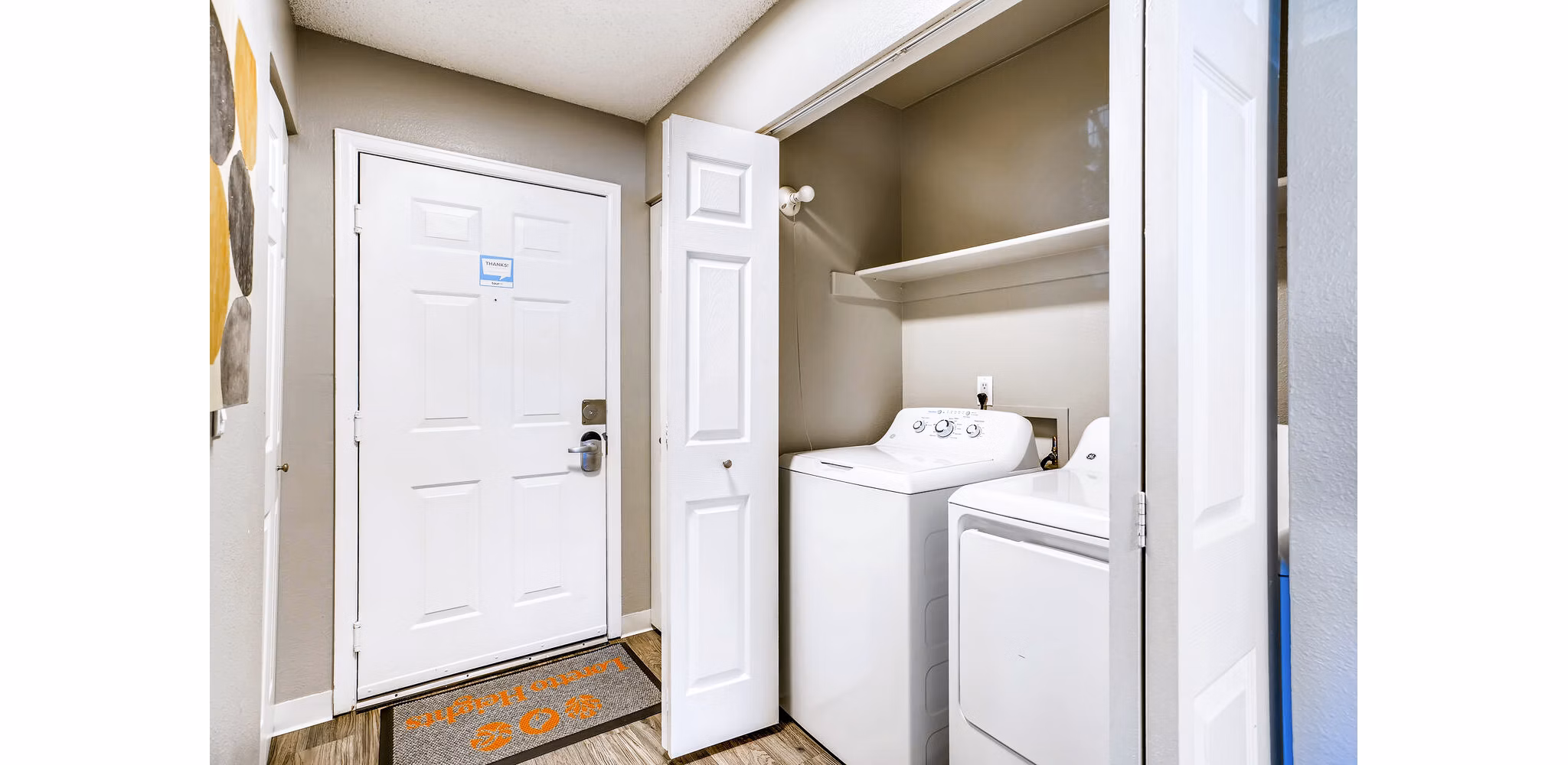 Laundry room with entrance to living room at Loretto Heights Apartments, offering convenience and luxury in open-concept design
