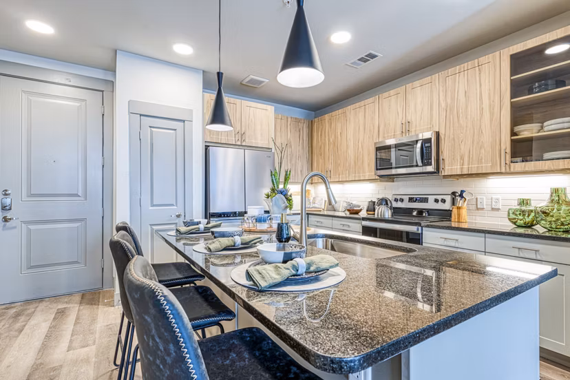 Modern kitchen with granite countertops and stainless steel appliances in The Banks of Springdale Apartments