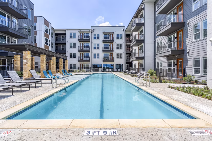 Inviting outdoor pool at The Banks of Springdale Apartments with lounge chairs and lush greenery offering luxury relaxation