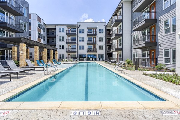 Inviting outdoor pool at The Banks of Springdale Apartments with lounge chairs and lush greenery offering luxury relaxation