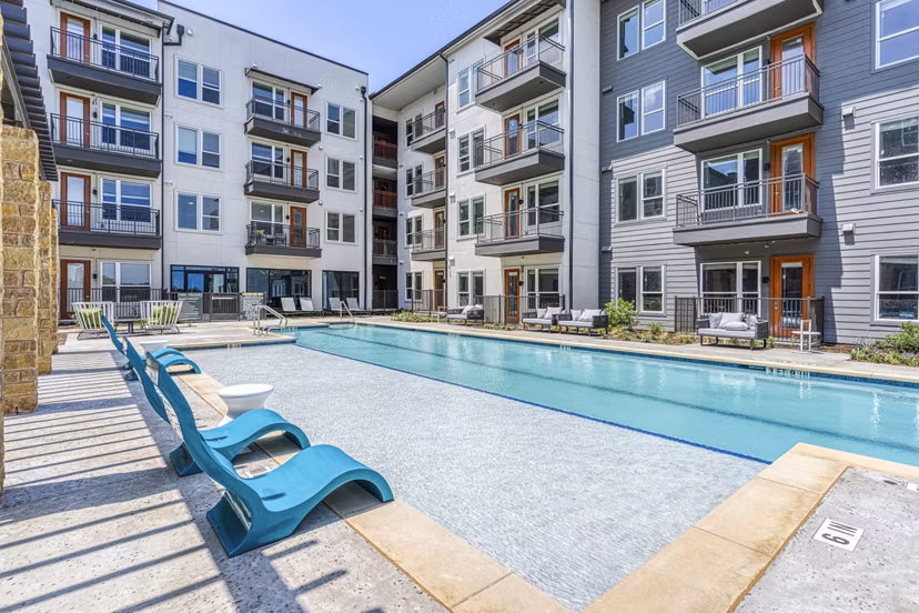 Modern outdoor pool with lounge chairs at The Banks of Springdale Apartments, offering luxury relaxation amid landscaped surroundings