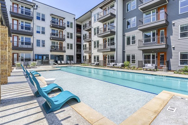 Modern outdoor pool with lounge chairs at The Banks of Springdale Apartments, offering luxury relaxation amid landscaped surroundings