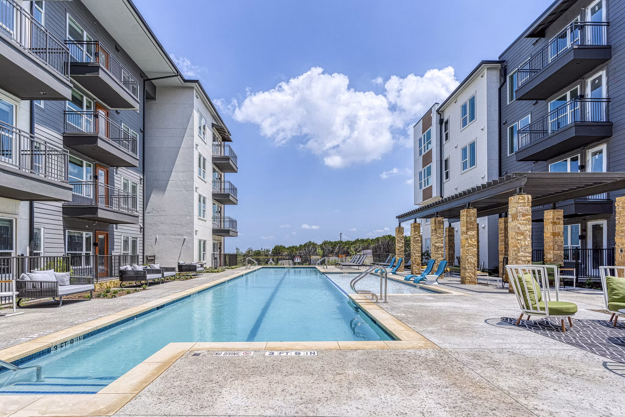 Luxurious pool at The Banks of Springdale Apartments featuring loungers and lush landscaping for relaxation and recreation