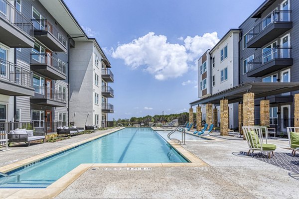 Luxurious pool at The Banks of Springdale Apartments featuring loungers and lush landscaping for relaxation and recreation