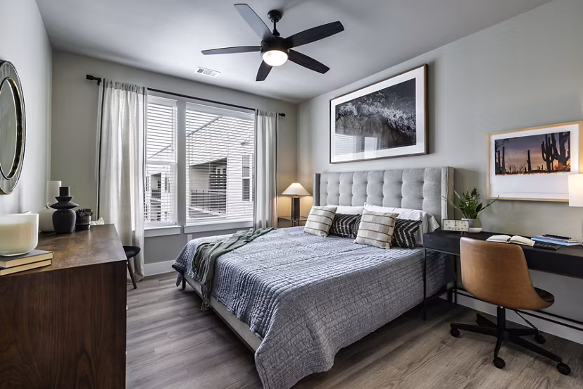 Modern bedroom featuring sleek furnishings and ample natural light in Urban East Apartments