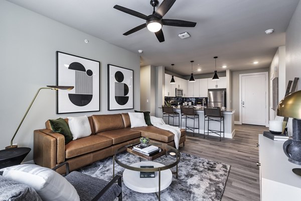 Modern living room with sleek furnishings and large windows at Urban East Apartments