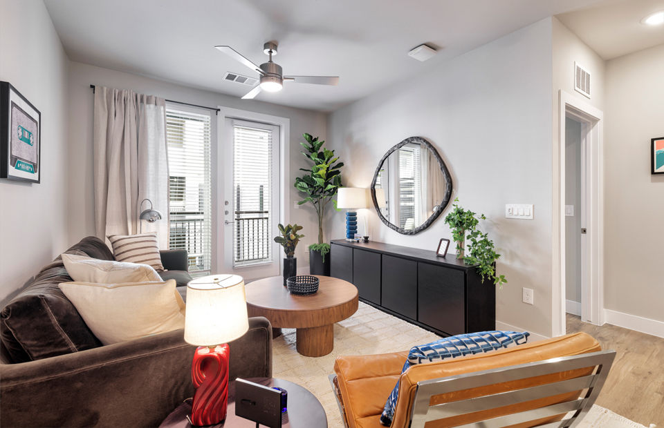 Modern living room with sleek furnishings and large windows at Urban East Apartments