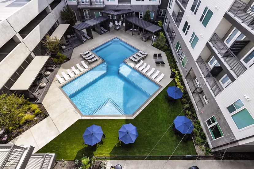 Resort-style pool at Urban East Apartments with lounge seating and palm trees