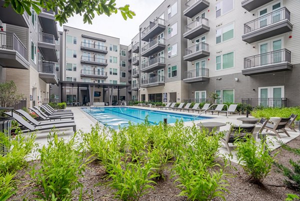 Resort-style pool at Urban East Apartments with lounge seating and palm trees