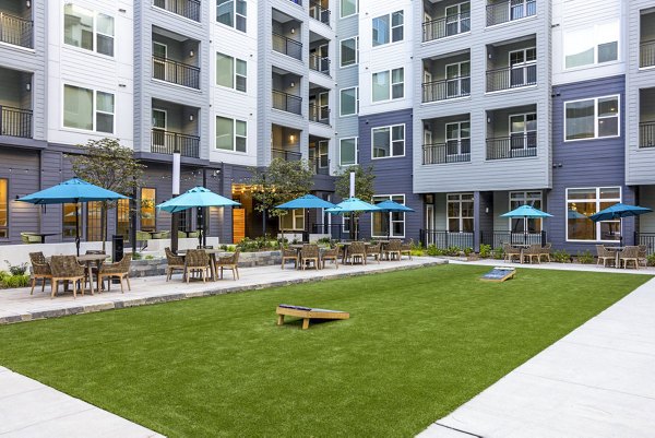 Outdoor patio and recreational area at Broadstone Optimist Park Apartments featuring modern seating and lush greenery