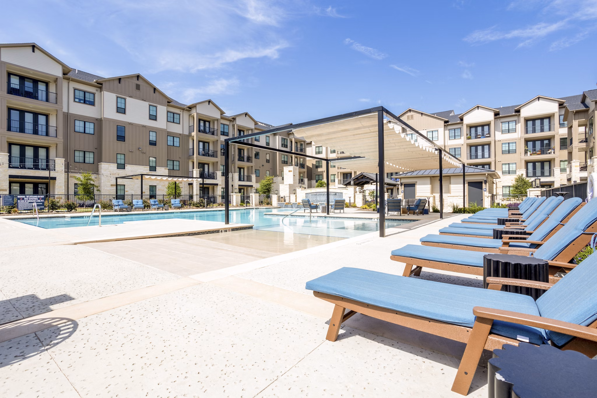 Poolside relaxation area with luxurious lounge chairs at Cadence Creek at Towne Lake Apartments
