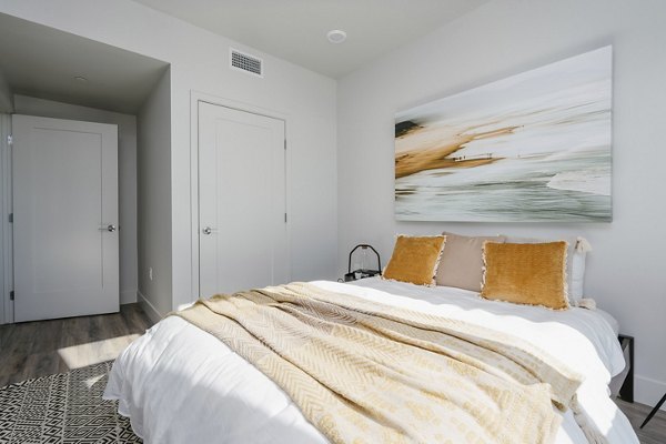 Cozy bedroom with modern decor at Assembly Apartments, featuring stylish furnishings and ample natural light