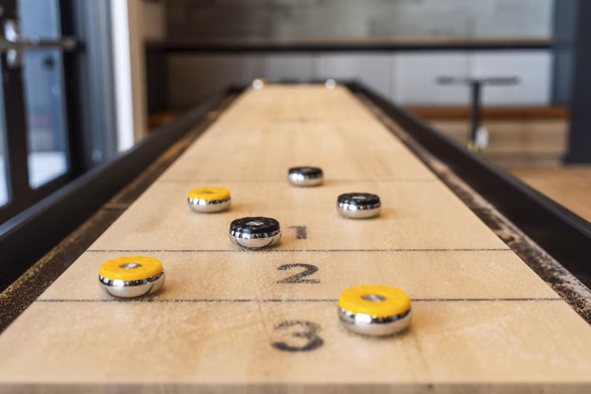 Game room with modern decor featuring pool table and lounge seating at Assembly Apartments
