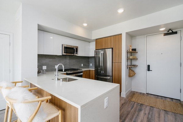 Modern kitchen featuring stainless steel appliances and granite countertops at Assembly Apartments