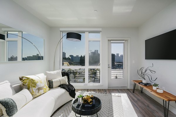 Spacious living room with modern furnishings and natural light at Assembly Apartments, luxury community by Greystar
