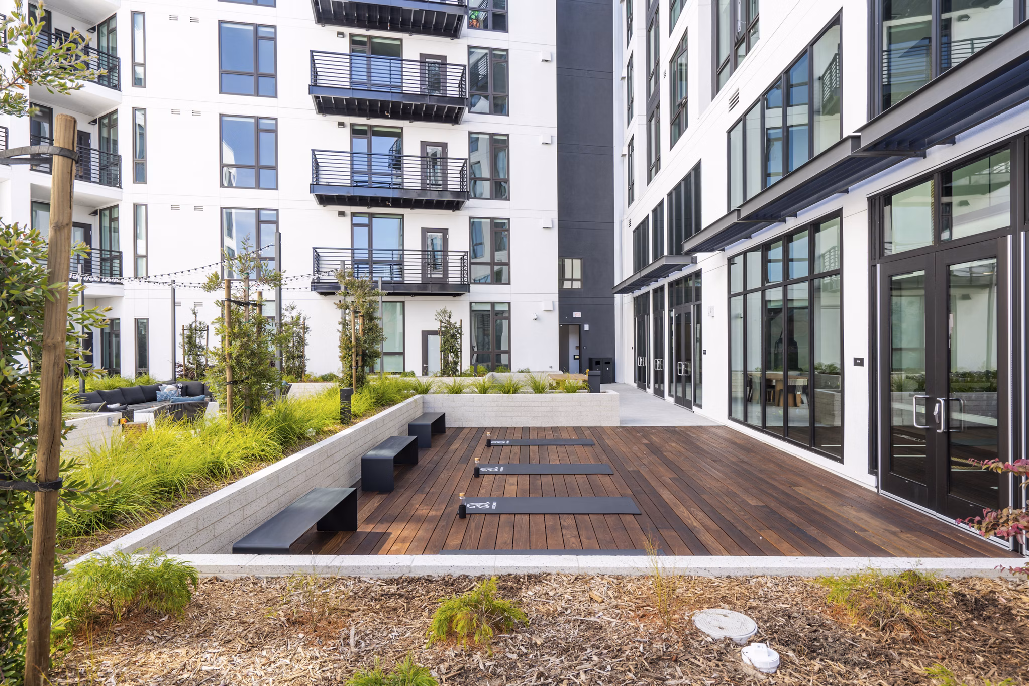 Outdoor sport court at Assembly Apartments featuring basketball hoops and tennis nets