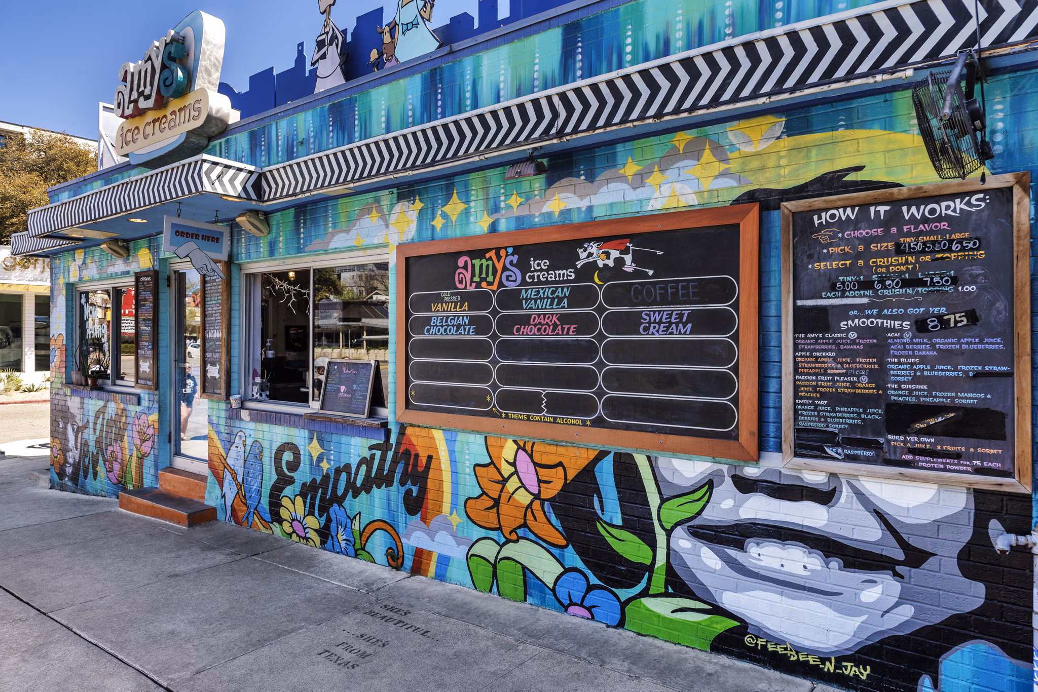 Ice cream shop with colorful murals and menu board in a lively community setting