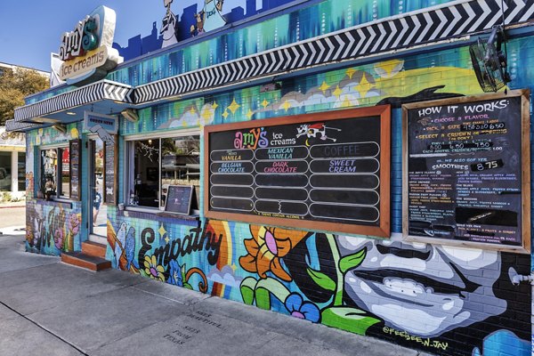 Ice cream shop with colorful murals and menu board in a lively community setting