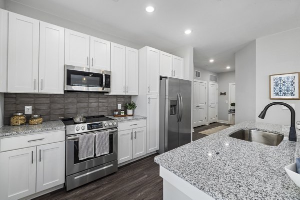Modern kitchen featuring stainless steel appliances and granite countertops in Element Barclay Station apartments