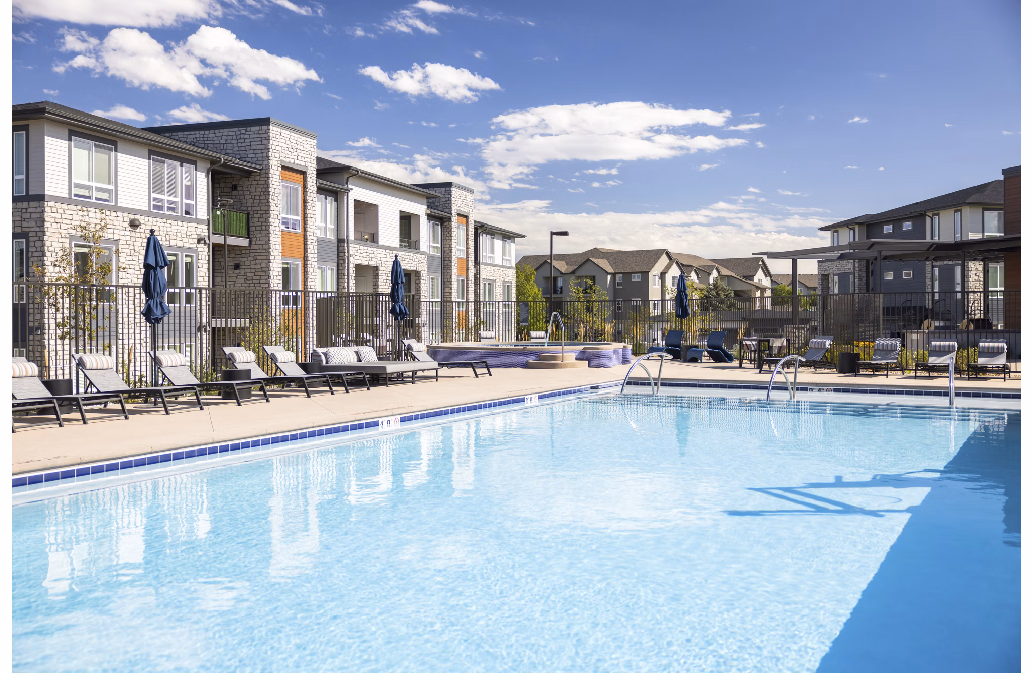 Modern outdoor pool at Fieldhouse Apartments with lounging areas and lush landscaping, perfect for relaxation and leisure