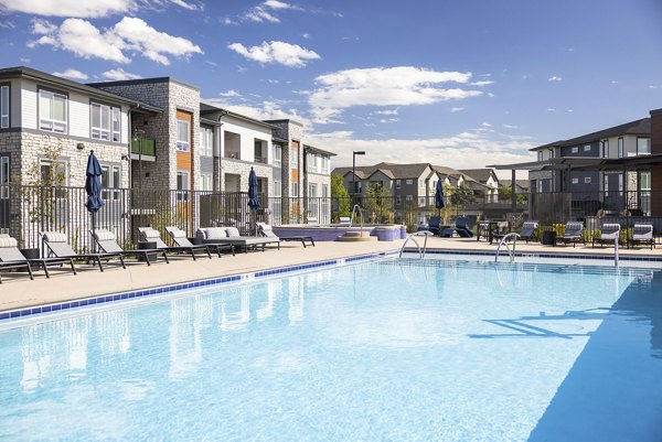 Modern outdoor pool at Fieldhouse Apartments with lounging areas and lush landscaping, perfect for relaxation and leisure