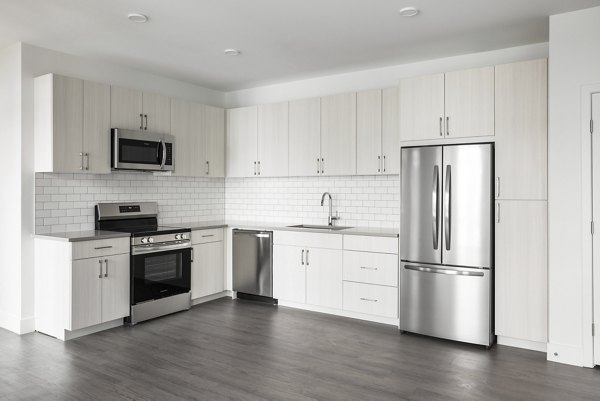 Modern kitchen with stainless steel appliances at Origin Apartments featuring sleek cabinetry and spacious countertops