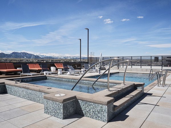 Luxury outdoor pool at Origin Apartments featuring lounge chairs and city views