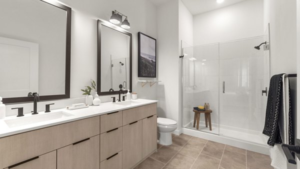 Modern bathroom featuring sleek fixtures and large vanity mirror at Infield Apartments