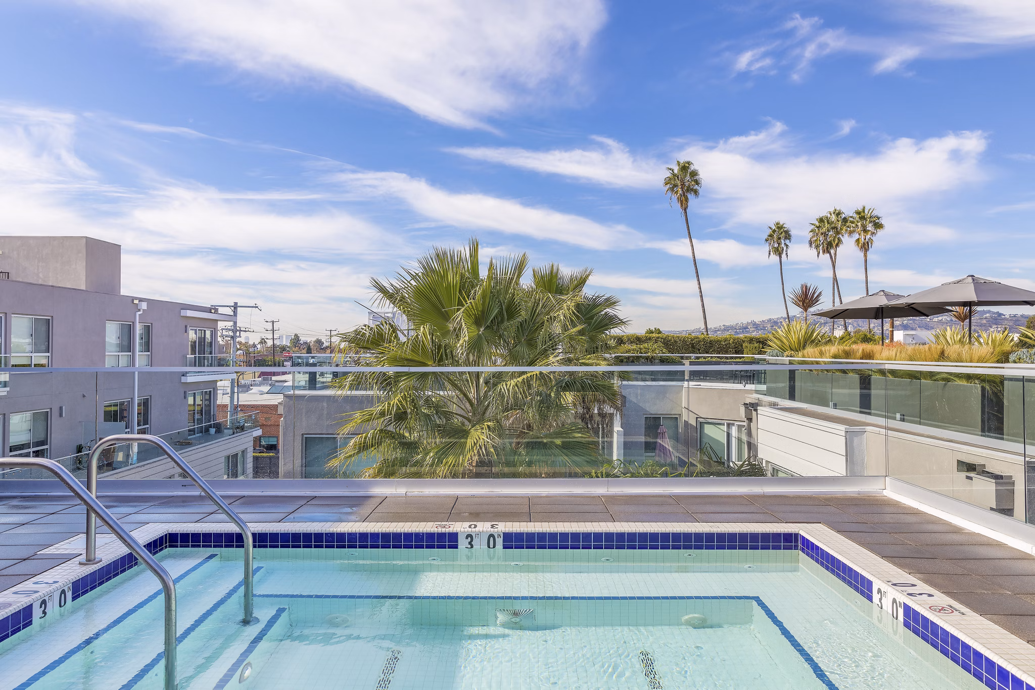 Expansive pool area at The LC Apartments with luxurious lounging options and scenic surroundings
