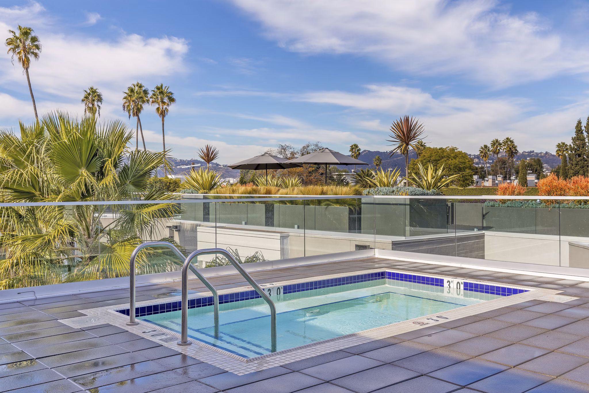Resort-style pool at The LC Apartments with sundeck and loungers