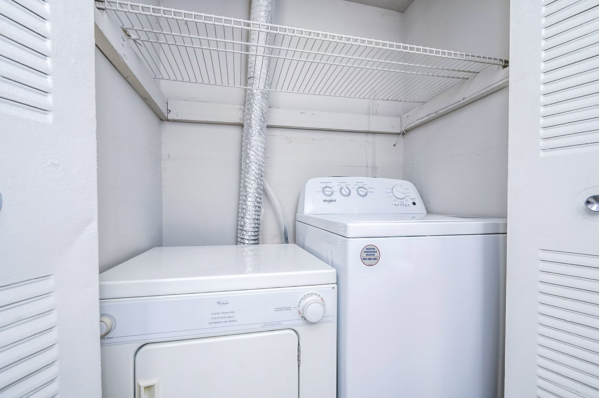 Laundry room equipped with modern machines at Woodshire Apartments, offering convenience for residents in a luxury setting