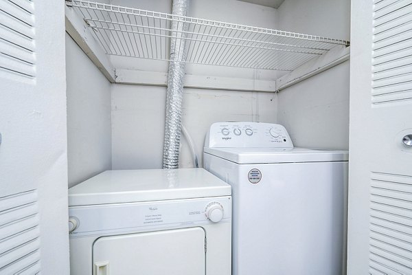 Laundry room equipped with modern machines at Woodshire Apartments, offering convenience for residents in a luxury setting