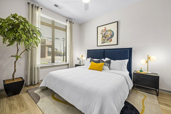 Cozy bedroom with modern decor and ample natural light at The Artreaux Apartments