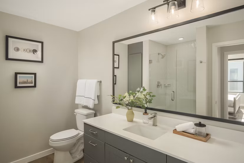 Modern bathroom with sleek fixtures and large mirror at Smith + Rio Apartments