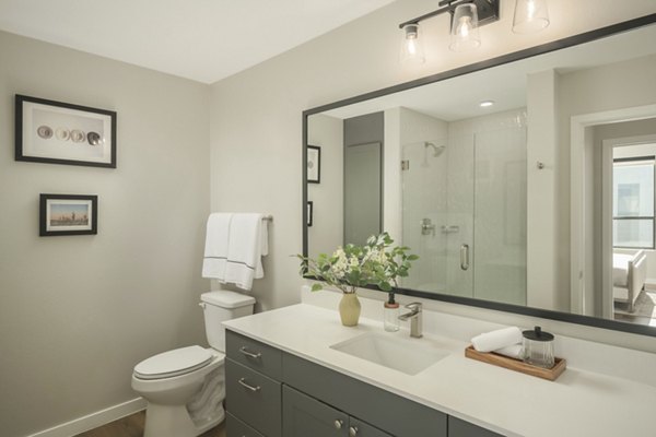 Modern bathroom with sleek fixtures and large mirror at Smith + Rio Apartments