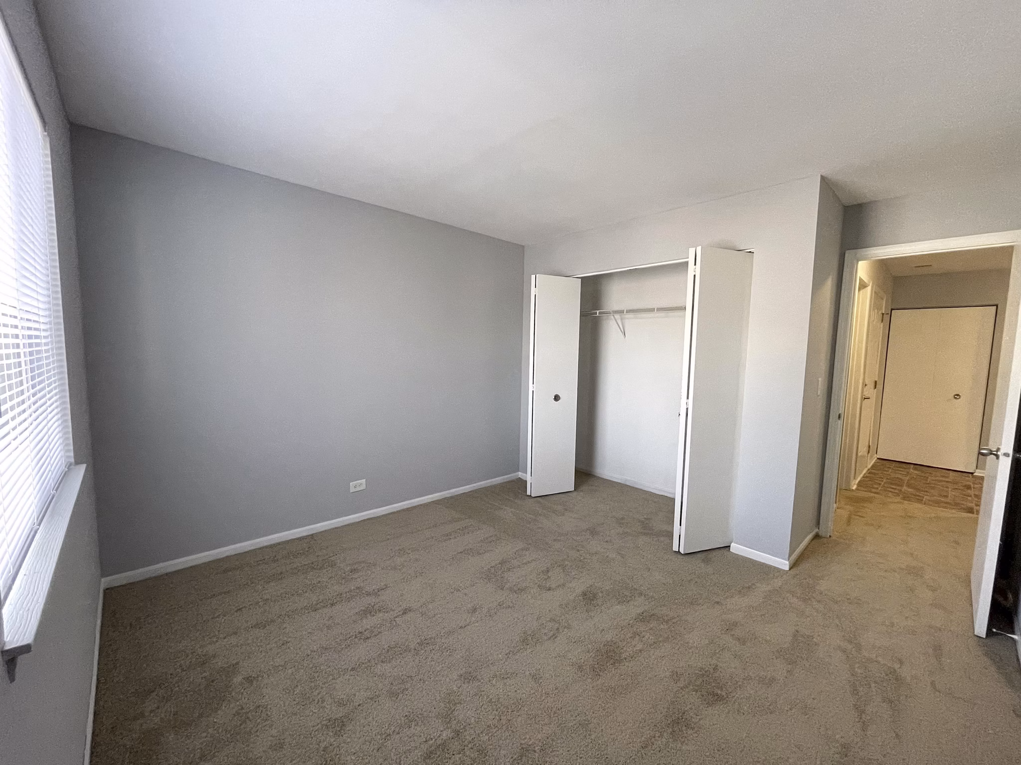 Bedroom featuring a cozy queen bed and large windows at Fox Pointe apartments