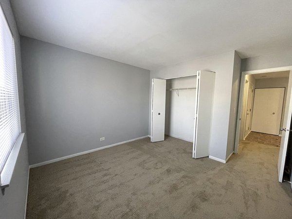 Bedroom featuring a cozy queen bed and large windows at Fox Pointe apartments