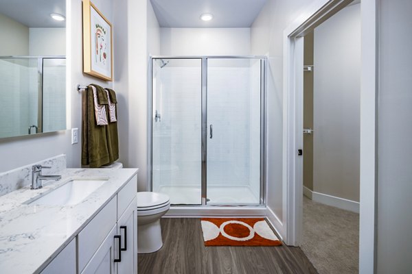 Modern bathroom featuring sleek fixtures and ample lighting in Soundwater Apartments